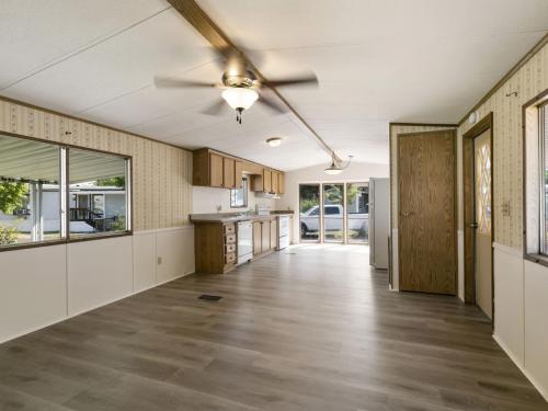 An empty kitchen with wood floors and a ceiling fan.