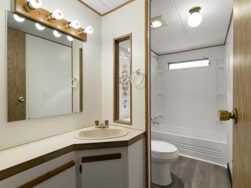 A bathroom with a toilet, sink and mirror.