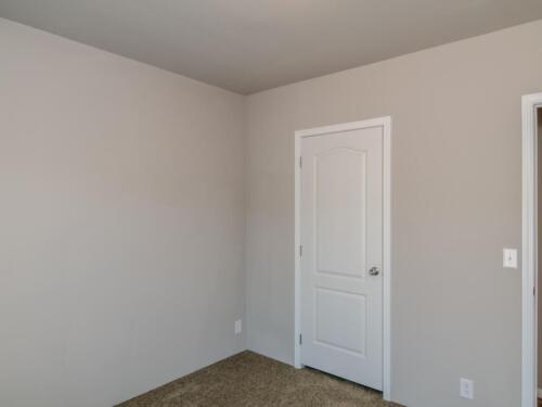 An empty room with a door and carpet.